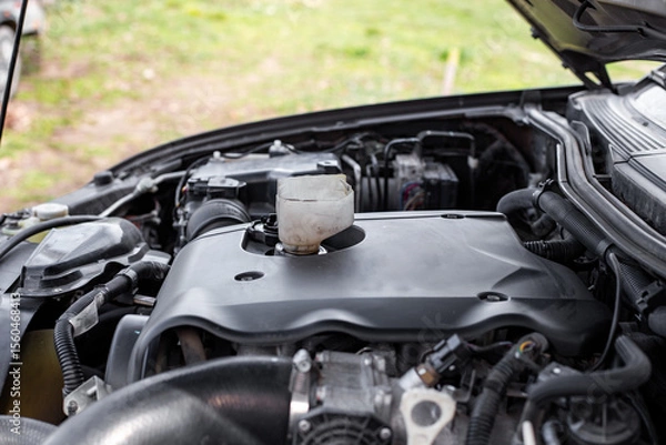 Fototapeta Car engine with hood open, funnel inserted to pour engine oil into engine oil filler neck
