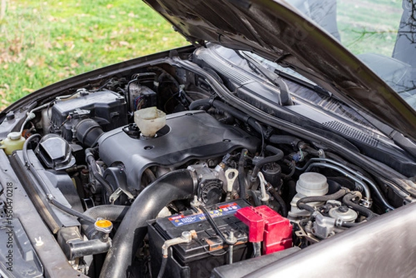 Fototapeta Car engine with open hood, engine components and funnel for filling engine oil