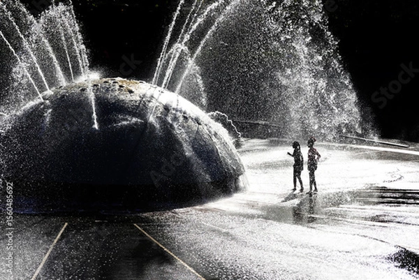 Obraz Silhouette of Kids Children Playing in Fountain in a City Park During the Summer