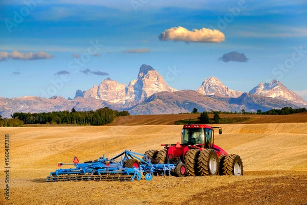 Obraz Tractor Farming Ground Harvesting Crops in Fall Autumn Teton Mountains Rugged Agriculture