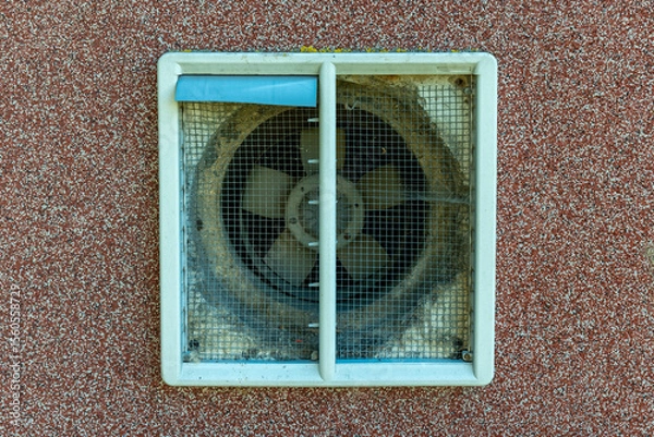 Fototapeta Decorative ventilation fan adds character to urban building with weathered charm in sunlight