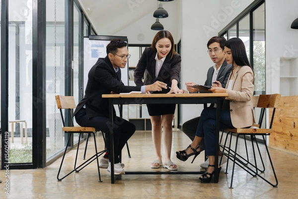 Fototapeta Focused Discussion: A group of business professionals collaborate, working together around a table in a bright, modern workspace, exchanging ideas and information