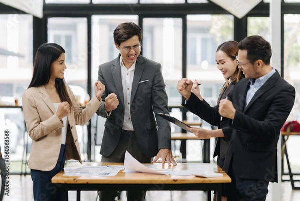 Fototapeta Team Victory in the Office: Capturing the dynamic essence of a contemporary office setting, where a diverse group of professionals celebrates a moment of triumph and unity.