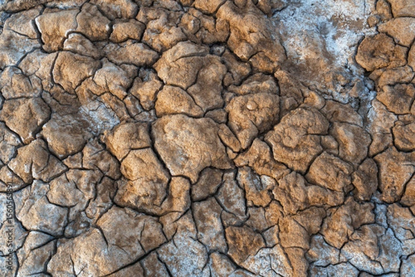 Fototapeta Textured background  of frozen soil, clay, ice, and snow on the salt lake of Baskunchak in Russia, viewed from above.