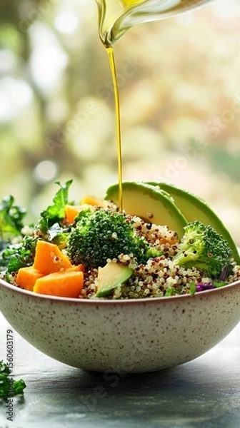 Obraz A bowl with quinoa, broccoli, avocado slices, roasted pumpkin cubes, and olive oil
