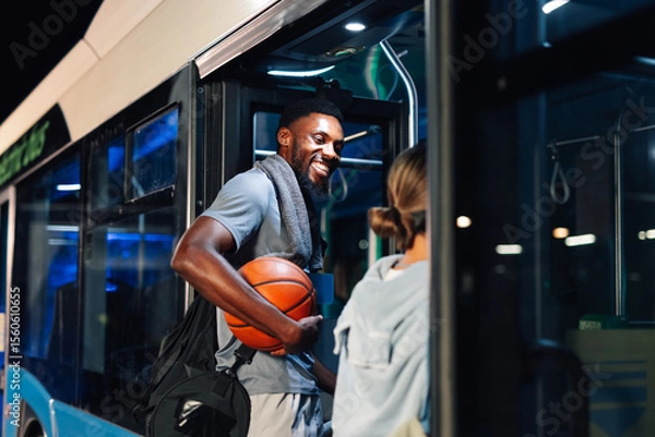 Fototapeta Basketball player exiting bus at night after training