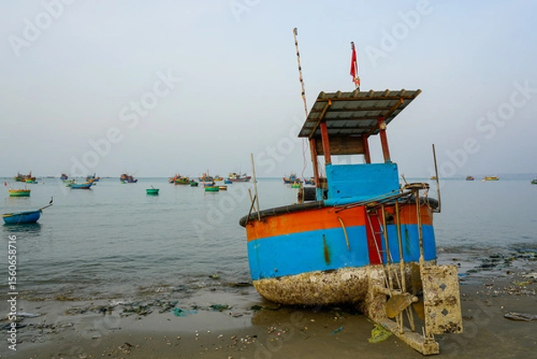 Fototapeta Colorful Fishing Boat Beached at Dawn in Mui Ne with Fleet in the Background