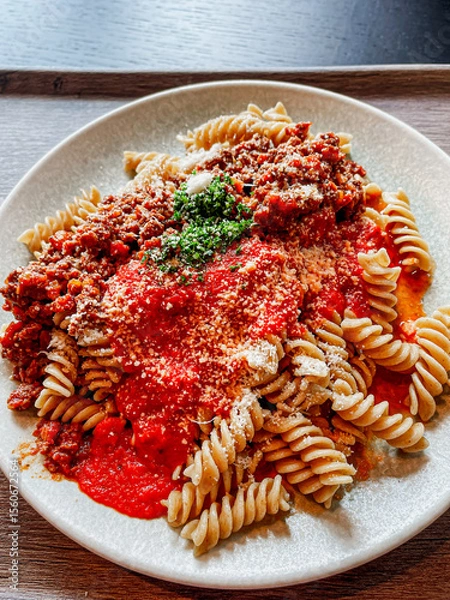 Fototapeta pasta with Bolognese and tomato sauce, parmesan cheese and garnish, top down view, close up, vertical shot