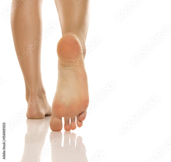 Fototapeta Close-up of woman's bare sole and heel while walking, studio shot on white background
