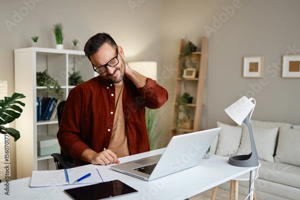 Obraz Man experiencing neck pain while working at desk