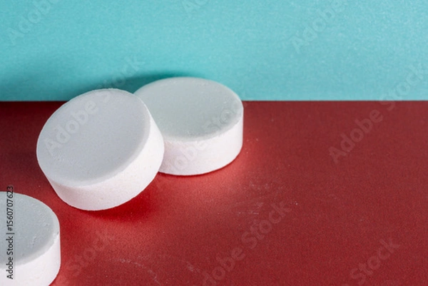 Obraz Three white medicine tablets standing isolated on red and blue pastel background as macro with copyspace