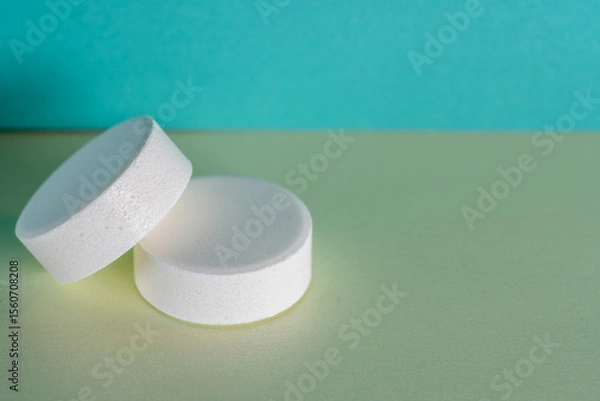 Obraz Two white medicine tablets laying isolated on green and blue pastel background as macro with copyspace 1
