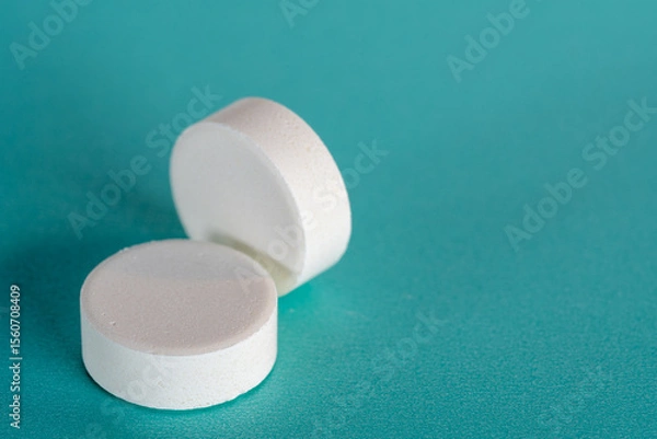 Obraz Two White medicine tablets standing and laying on side isolated on blue pastel background as macro