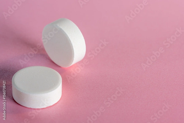 Obraz Two white medicine tablets standing on side and laying isolated on pink pastel background as macro 1