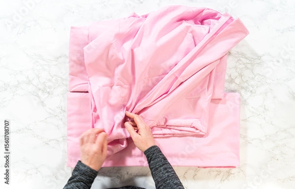 Obraz Hands Folding Pink Bed Sheet on Marble Surface