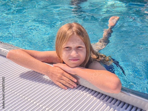 Fototapeta A child is joyfully swimming in a refreshing pool under the bright sunlight shining down