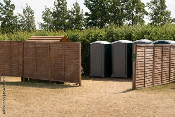 Obraz Gloucestershire England UK. 30.06.2025. Toilet block shared by. men and women having the privacy of a fenced screen in the English countryside.