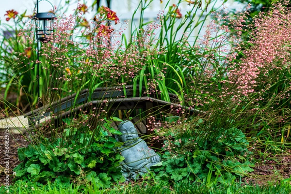 Obraz Buddha statue in flower garden with wooden bridge on sunny day