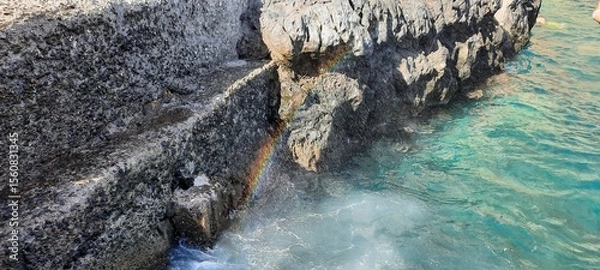 Obraz A rainbow emerges when it rains. rainbow with splashing water of a sea. Art of Nature Rainbow in water droplets. 