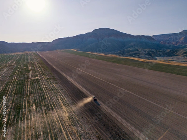Fototapeta Nallihan Bird Sanctuary Beypazari Ankara Turkey Aerial view of a tractor working a field, preparing for planting. An expansive, flat agricultural field is depicted from a high-altitude perspective.
