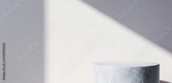 Fototapeta Cylinder pedestal against a white wall with a shadow pattern.