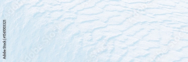 Fototapeta Wide panoramic winter background with snowy ground. Natural snow texture. Wind sculpted patterns on snow surface.