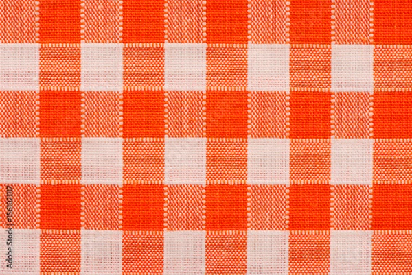 Obraz Close-up of orange and white gingham checkered fabric with a rustic woven texture, perfect for picnic tablecloths, farmhouse decor, vintage kitchen style, and cheerful home textile backgrounds.
