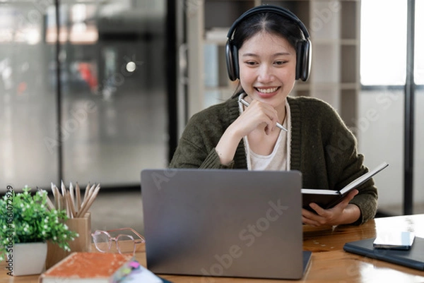Obraz Hipster teen girl school student  wear headphone write notes watch video online webinar learn on laptop elearning course video conference