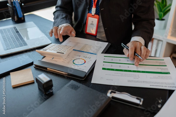 Obraz a businessman reviews the company's financial documents in his office, the accountant is rushing to check the figures in the documents before submitting them to the tax office