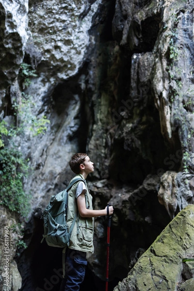 Obraz A determined hiker stands confidently with a trekking pole inside a rocky canyon, surrounded by rugged cliffs. The scene symbolizes adventure, strength, and the spirit of exploration in nature.