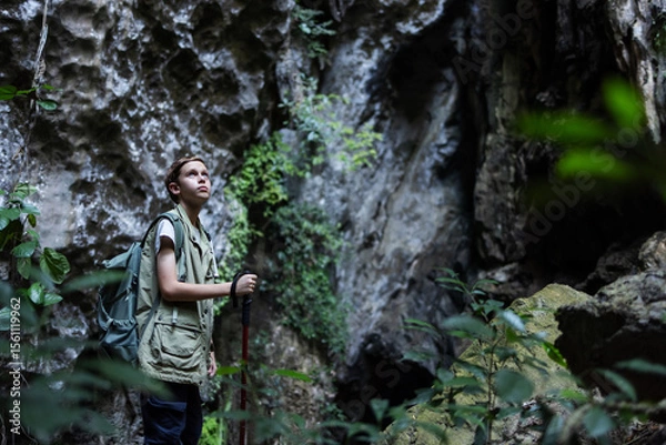 Obraz A determined hiker stands confidently with a trekking pole inside a rocky canyon, surrounded by rugged cliffs. The scene symbolizes adventure, strength, and the spirit of exploration in nature.