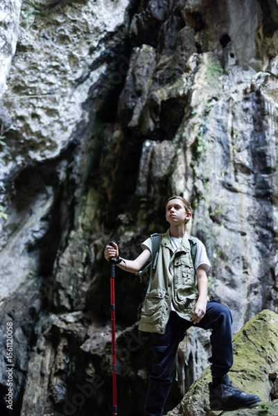 Obraz A determined hiker stands confidently with a trekking pole inside a rocky canyon, surrounded by rugged cliffs. The scene symbolizes adventure, strength, and the spirit of exploration in nature.
