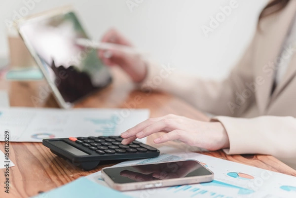 Obraz Business professional analyzing financial data with calculator and tablet on wooden desk