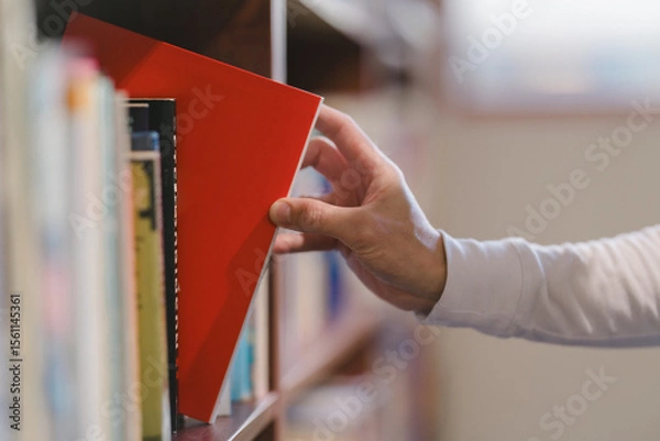 Fototapeta right hand choosing and picking book in public library.