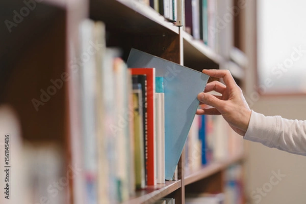 Fototapeta right hand choosing and picking book in public library.