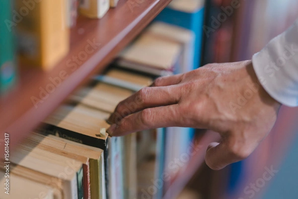 Fototapeta right hand choosing and picking book in public library.