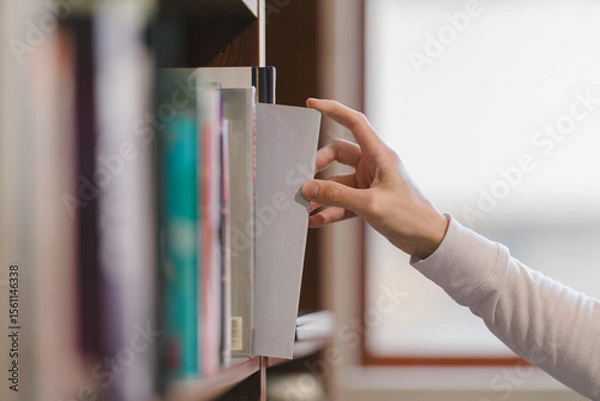 Fototapeta right hand choosing and picking book in public library.