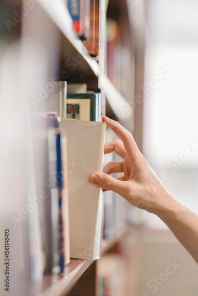 Fototapeta right hand choosing and picking book in public library.