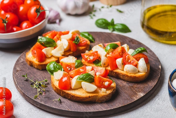 Fototapeta Bruschetta caprese with cherry tomatoes and mozzarella garnished with basil