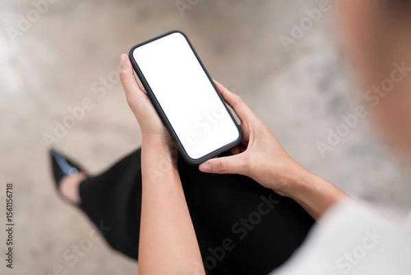 Fototapeta Top view Woman sitting and holding blank screen mock up mobile phone