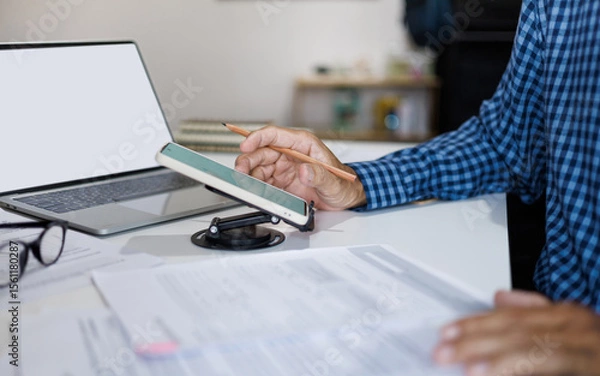 Fototapeta asian businessman working on desk using smart phone and laptop review business documents in office