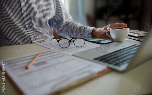 Fototapeta asian businessman have coffee drink while working and meeting online with business group via laptop on desk at home office, working at home concept