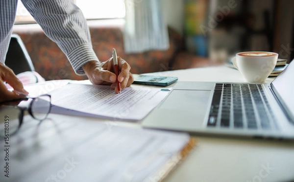 Fototapeta asian businessman standing at desk office checking document report and business contract using laptop working and meeting online