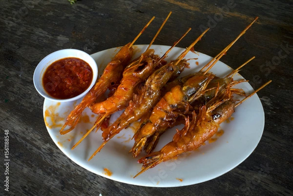 Fototapeta Shrimp satay with chili sauce at white plate on an old wooden table