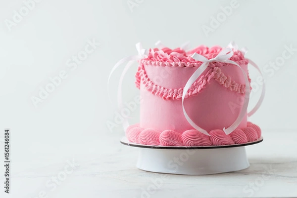 Fototapeta Delicate lambeth style birthday cake with pink cream cheese frosting decorated with cream tracery and happy birthday text on top. White background