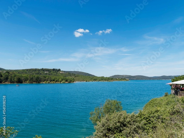 Fototapeta Lac de Sainte-Croix au pied des gorges du Verdon. Vue sur l'embouchure du ravin de la Combe face au village de Bauduen adossé à la falaise rocheuse
