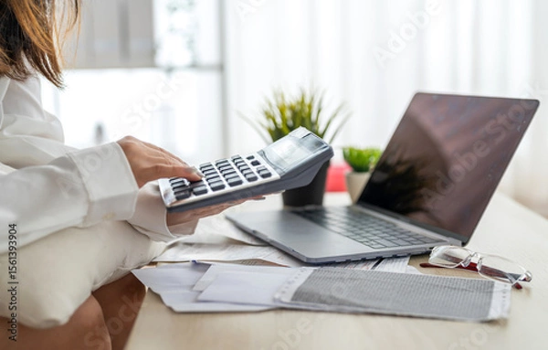 Fototapeta Human use calculator and calculate bills and paying bill, credit card, tax and vat, payment, concept of money management and business report with financial documents, financial accounting concept