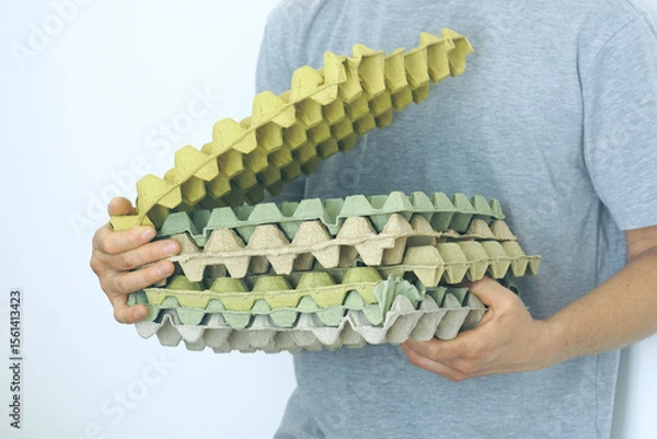 Fototapeta Used egg trays for reuse. A man holding empty egg cartons, symbolizing sustainable food packaging and smart household consumption practices. Ideal for topics on eco-packaging and grocery habits