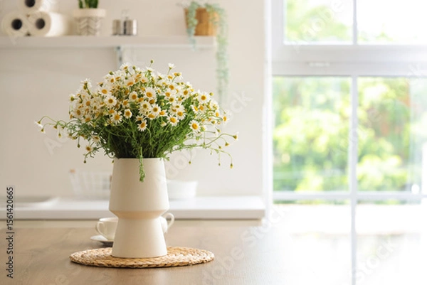 Fototapeta Vase with chamomiles on table in kitchen