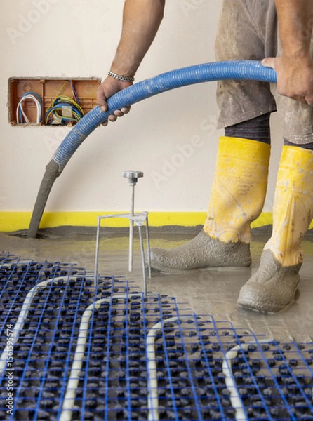 Fototapeta Man pouring concrete over floor heating installation in a new building. Modern construction system